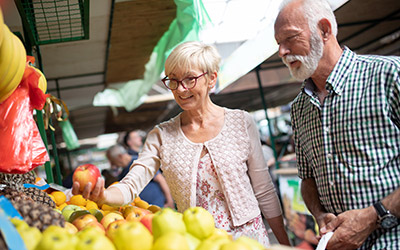 older couple picking fruit from outdoor market